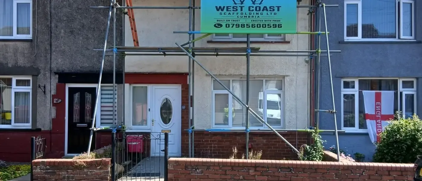 Full-elevation scaffold across a terrace with the West Coast Scaffolding banner tied to the top lift.