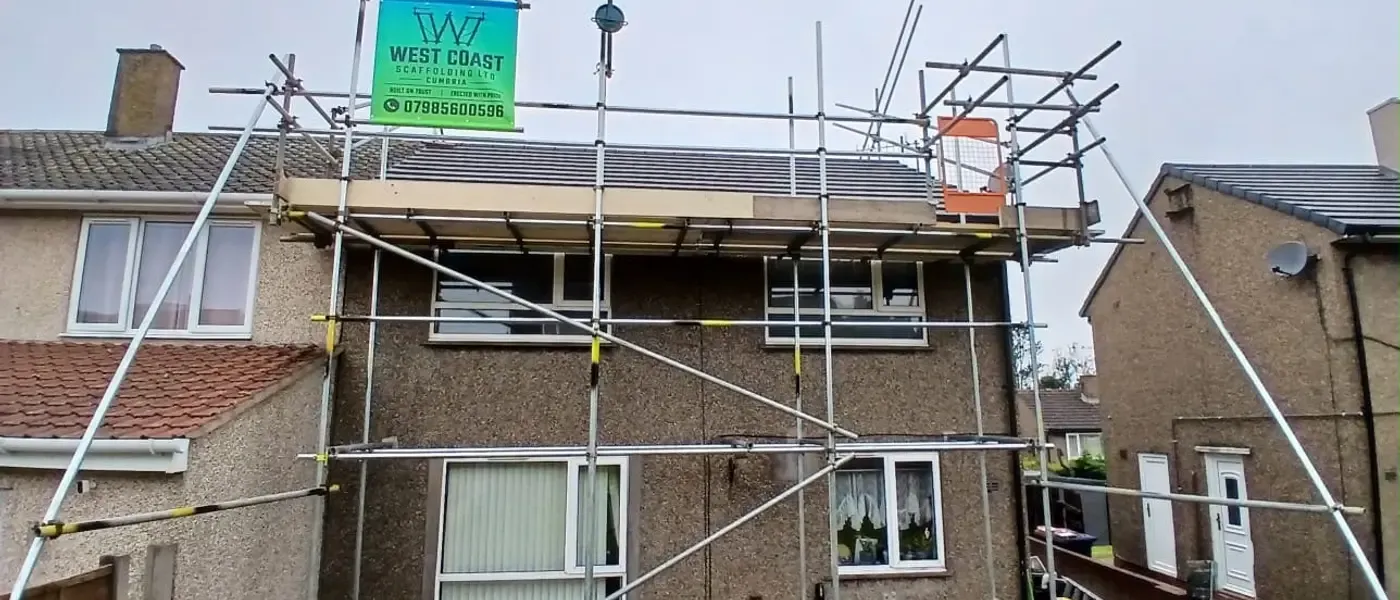 Scaffold to a semi-detached house, banner on the top lift and a boarded platform running the full elevation.