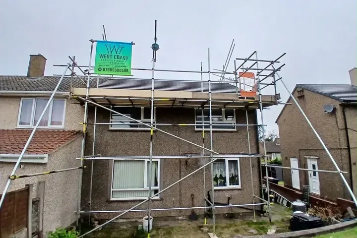 Scaffold to a semi-detached house, banner on the top lift and a boarded platform running the full elevation.