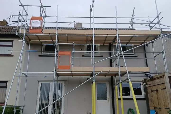 Scaffold to a rendered semi with two boarded lifts and orange debris netting at the top.