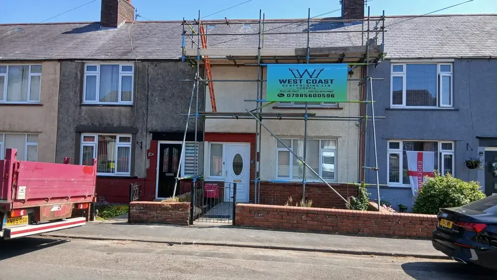 Terrace frontage scaffolded to the eaves with the company banner up and a tipper wagon on the road.
