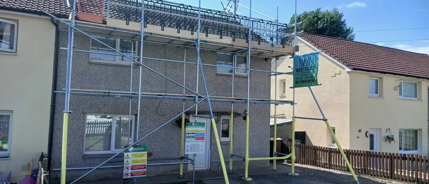 Scaffold to the front of a rendered semi, banner up, boarded lift at eaves level and the drive kept clear.