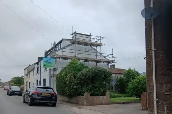 Scaffold to a house seen from the road, boarded lifts to the eaves and the banner on the top lift.